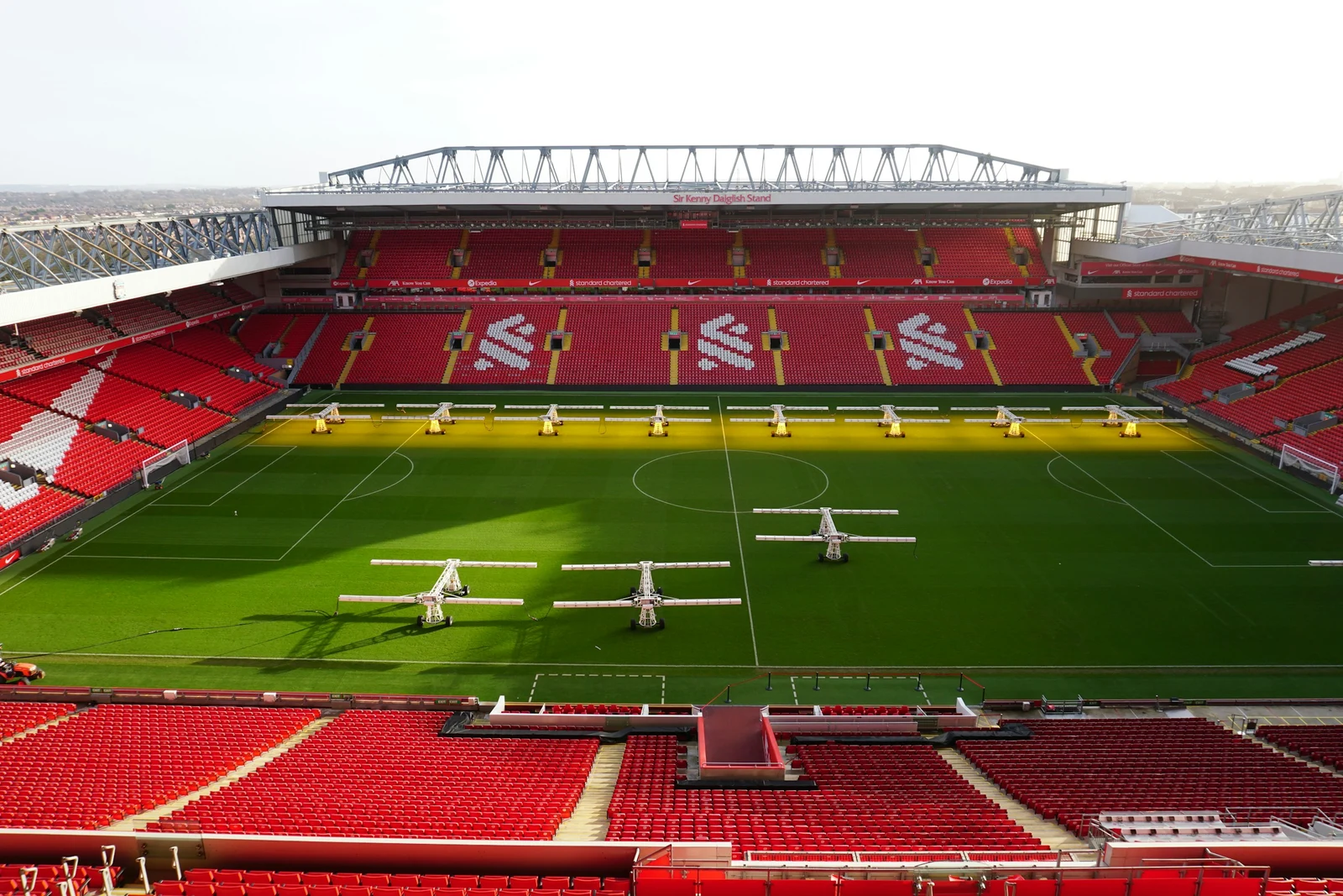 Liverpool FC’s Anfield stadium in England, with red seating, Liver bird emblems and the pitch.